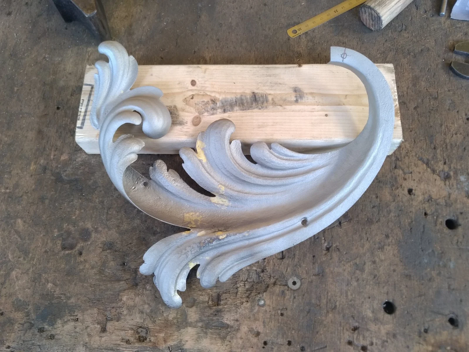 Feuille d’acanthe forgée posée sur une cale de bois, établi de l’atelier