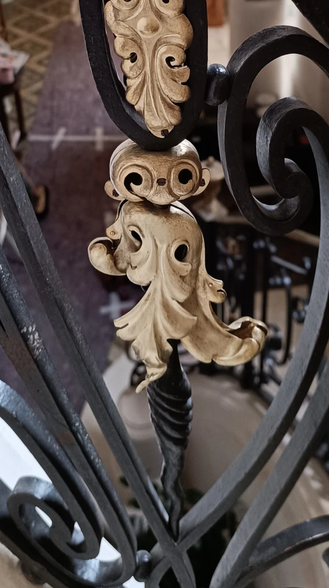 Feuille d’acanthe en laiton doré reposée sur les volutes noires d’une rampe ancienne