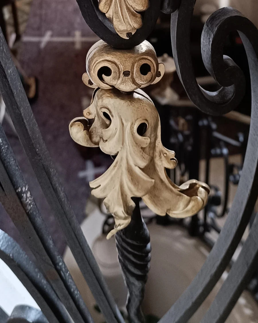 Feuille d’acanthe en laiton doré reposée sur les volutes noires d’une rampe ancienne