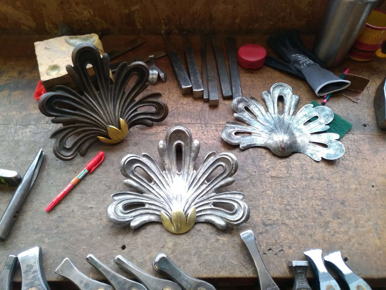 Trois rocailles en fer forgé, dont une dorée, avec outils et burins sur l’établi