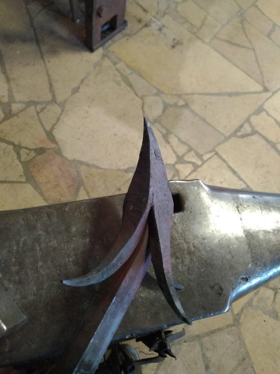Feuille de chardon en fer, pointe relevée, maintenue sur l’enclume pour la soudure au feu